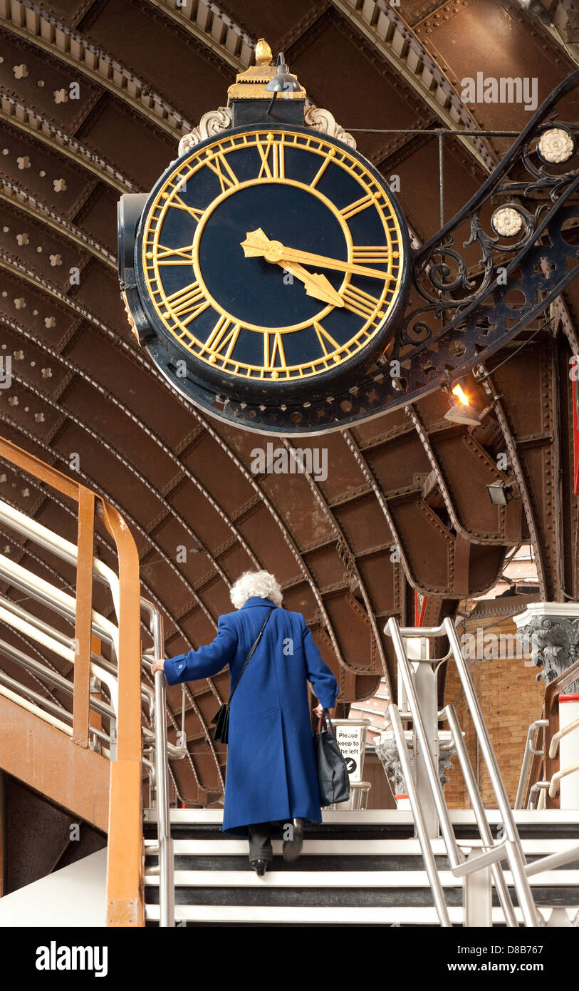 Una vecchia donna sotto il clock presso la stazione ferroviaria di York - concetto di tempo vecchiaia anziani in esecuzione fuori del tempo Foto Stock