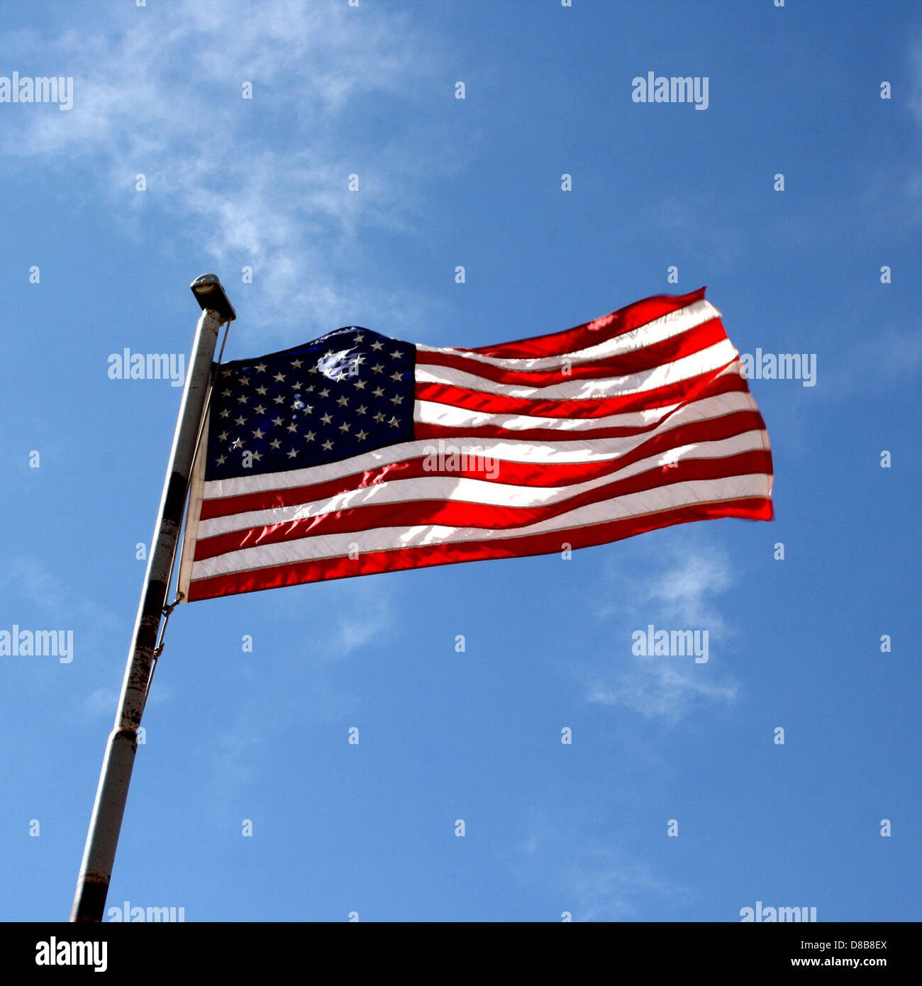 La bandiera americana è esposta contro un cielo azzurro, simboleggiando il patriottismo e l'orgoglio nazionale. La bandiera presenta strisce rosse e bianche con un campo di stelle che rappresentano gli stati. Foto Stock