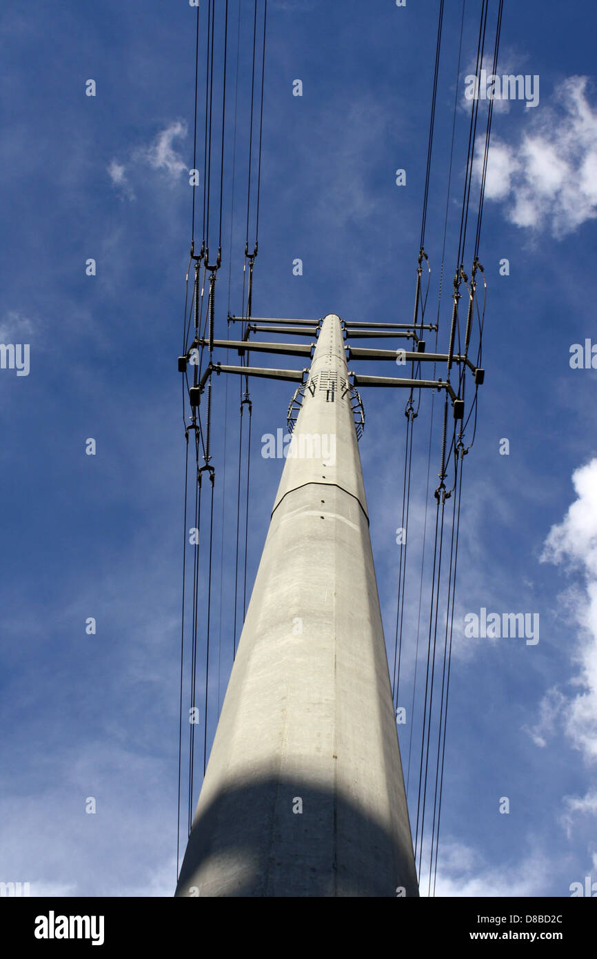Una foto che mostra i cavi di trasmissione elettrica e un palo alto, che si estende attraverso un cielo limpido. Questa immagine rappresenta l'infrastruttura di distribuzione dell'energia elettrica, vitale per l'alimentazione di case e aziende. Foto Stock