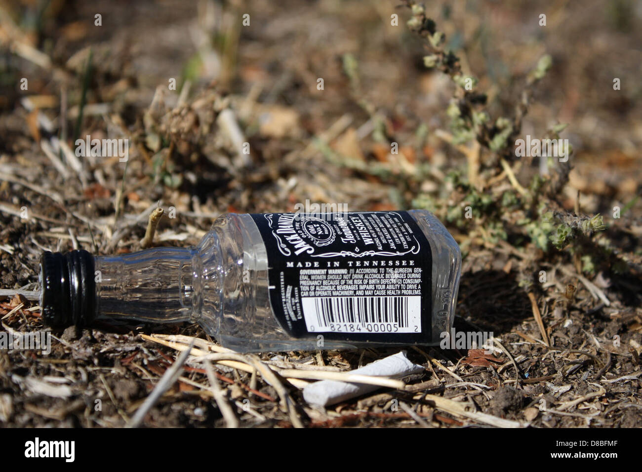 Una bottiglia di whisky di Jack Daniel collocata a terra, generalmente utilizzata per immagini promozionali o di stile di vita, associata al famoso marchio di whisky. Foto Stock