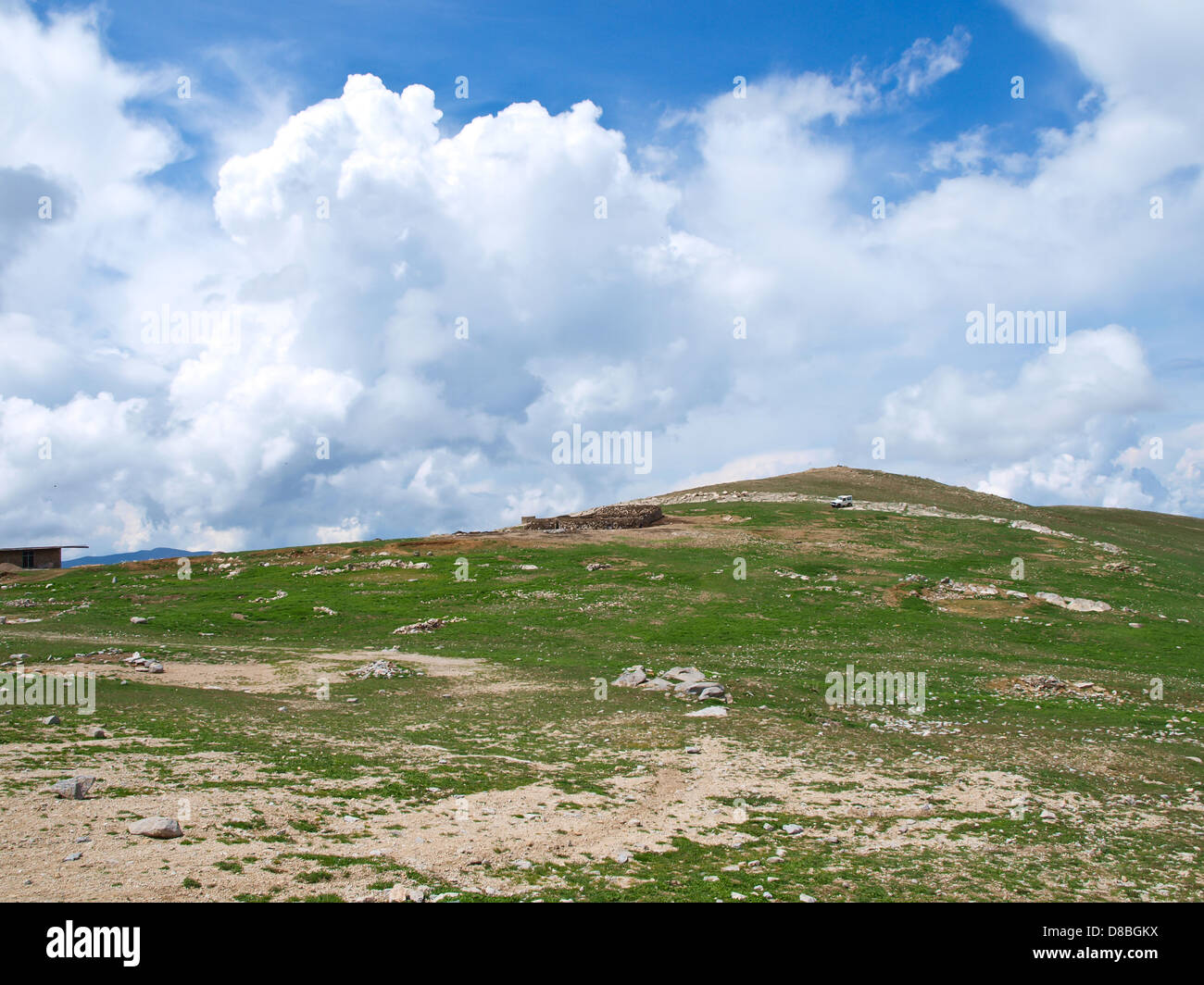 Erba verde collina e nuvoloso cielo blu Foto Stock