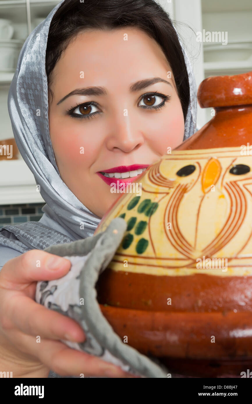 Marocchina tradizionale donna immigrati in Europa tajine di cottura durante il Ramadan nella sua cucina moderna Foto Stock