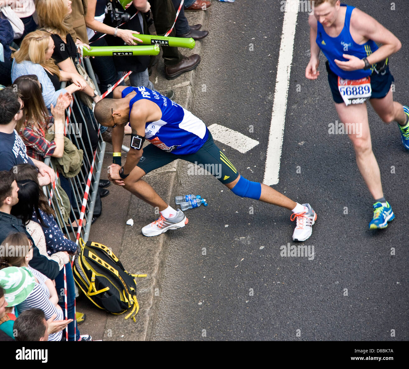 Runner atleta concorrente di fermarsi per allungare le gambe durante 2013 maratona di Londra Inghilterra Europa Foto Stock