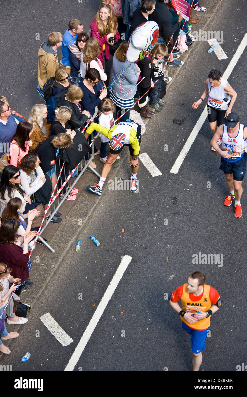 Runner atleta concorrente di fermarsi per allungare le gambe durante 2013 maratona di Londra Victoria Embankment Inghilterra Europa Foto Stock