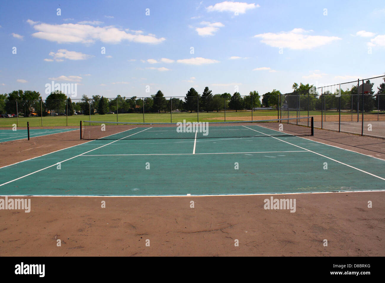 Campi da tennis situati all'interno di un parco pubblico, con campi puliti e ben tenuti pronti all'uso. L'ambiente all'aperto è perfetto per le attività ricreative e i tornei locali. Foto Stock