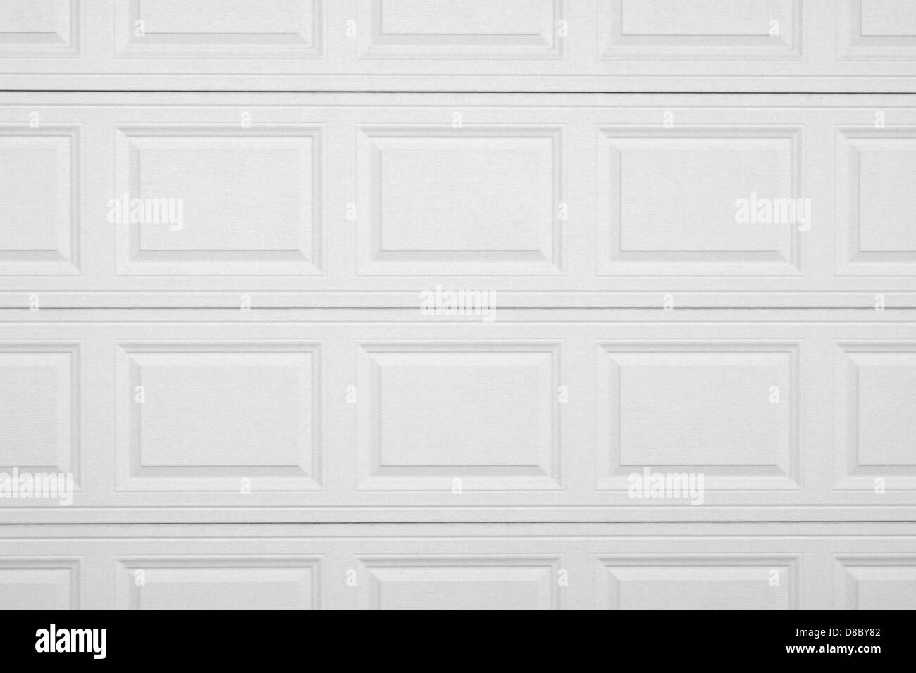 Un primo piano di una porta bianca del garage, che si concentra sulla sua superficie ruvida. L'immagine mostra lo schema della portiera, che può includere linee orizzontali o un design del pannello, creando un'estetica pulita e liscia. Foto Stock