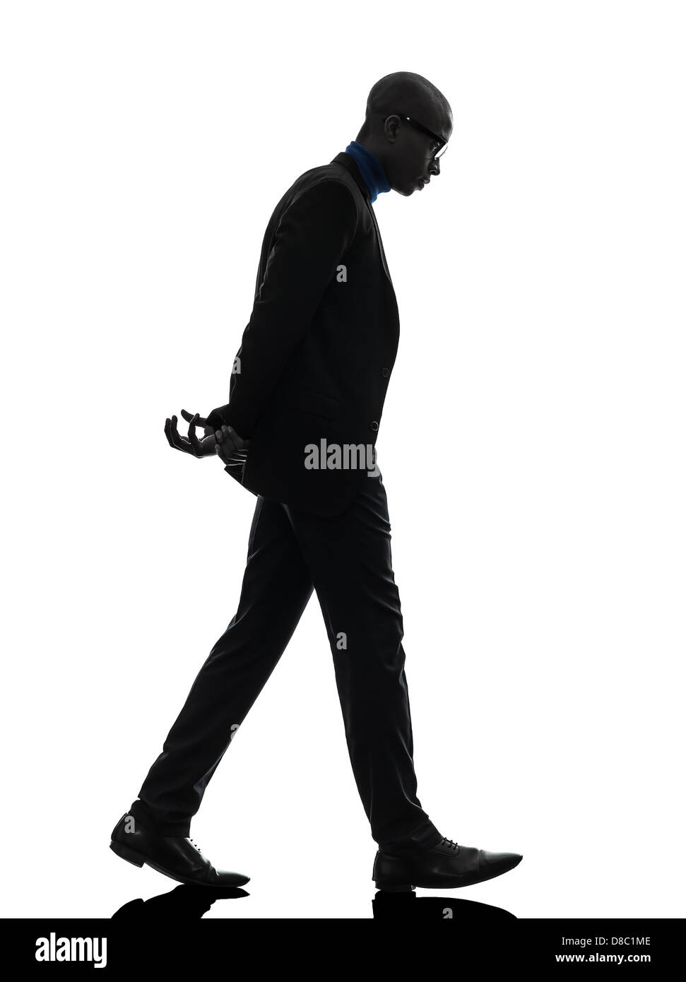 Uno nero africano uomo a camminare guardando giù in silhouette studio su sfondo bianco Foto Stock