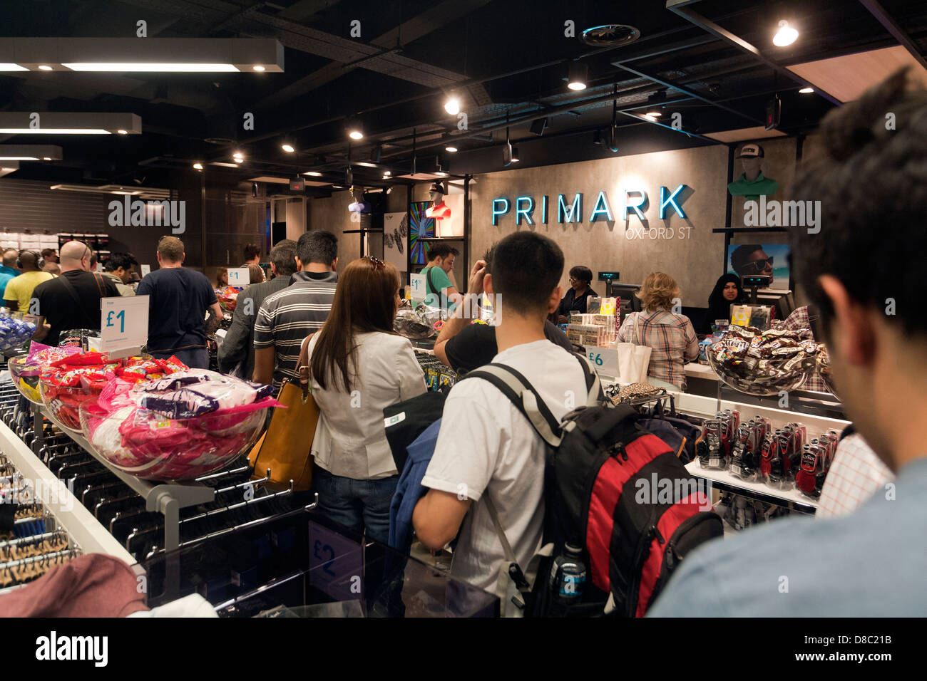 La gente in coda per il pagamento in busy Primark rivenditore shop, London REGNO UNITO Foto Stock