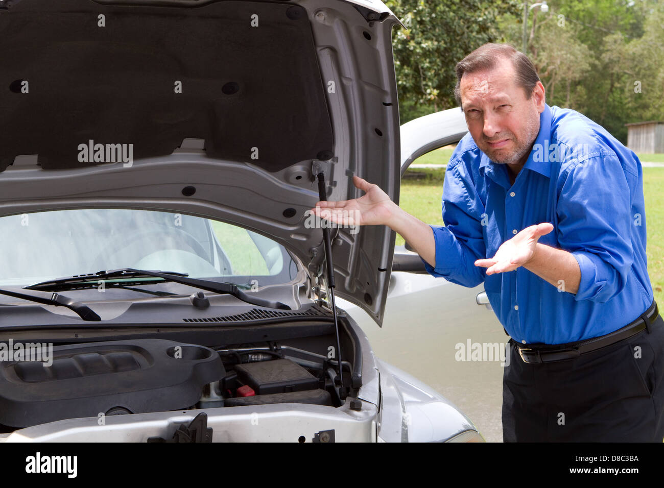 Senior l uomo ha bisogno di aiuto e di gesti in frustrazione circa la sua auto che è rotto e che necessitano di un intervento di riparazione. Foto Stock