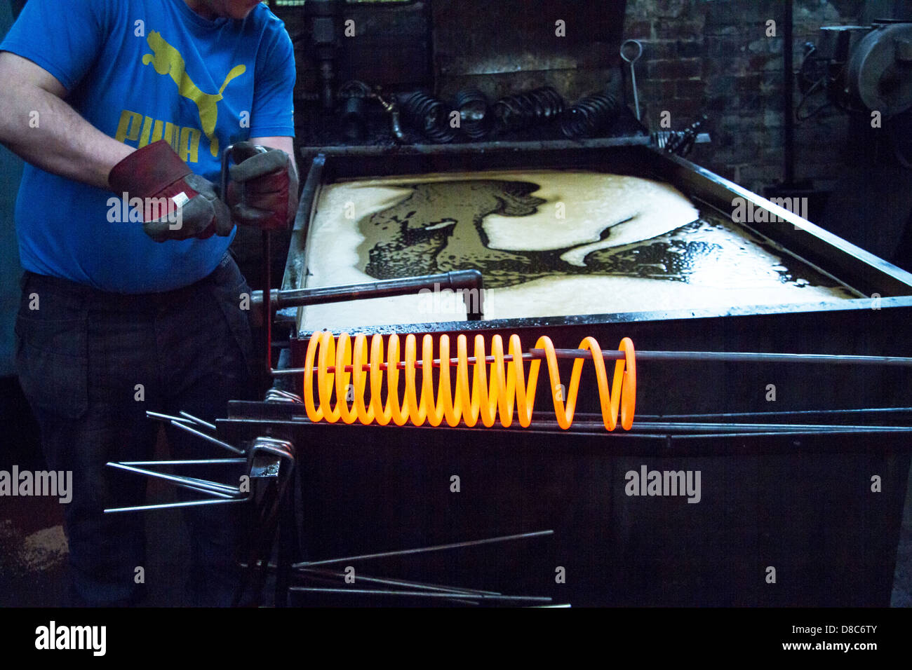 Le bobine a molla di sospensione essendo abbassata in olio bagno di tempra in UK Manufacturing Company. Foto Stock