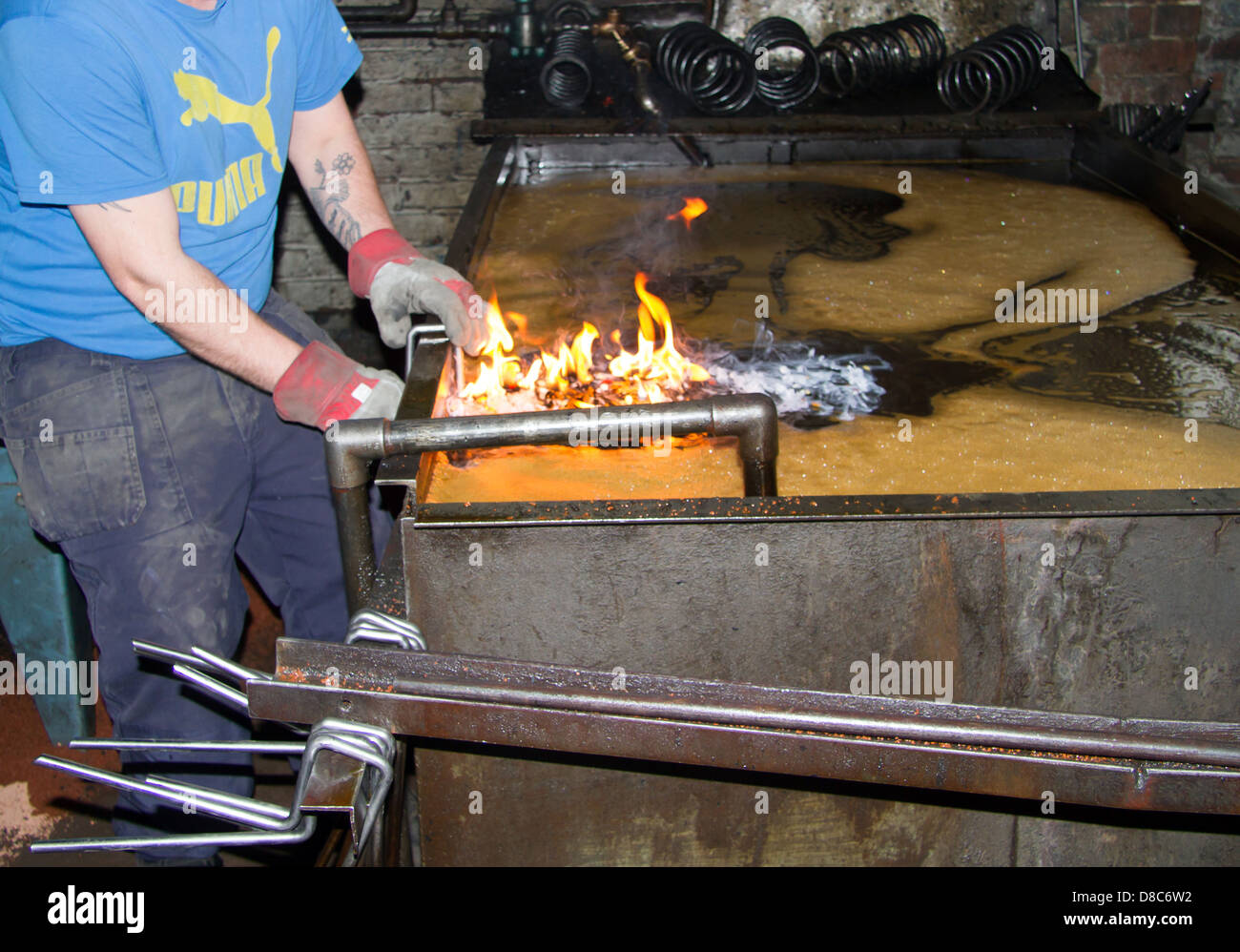 Le bobine a molla di sospensione essendo abbassata in olio bagno di tempra in UK Manufacturing Company. Foto Stock