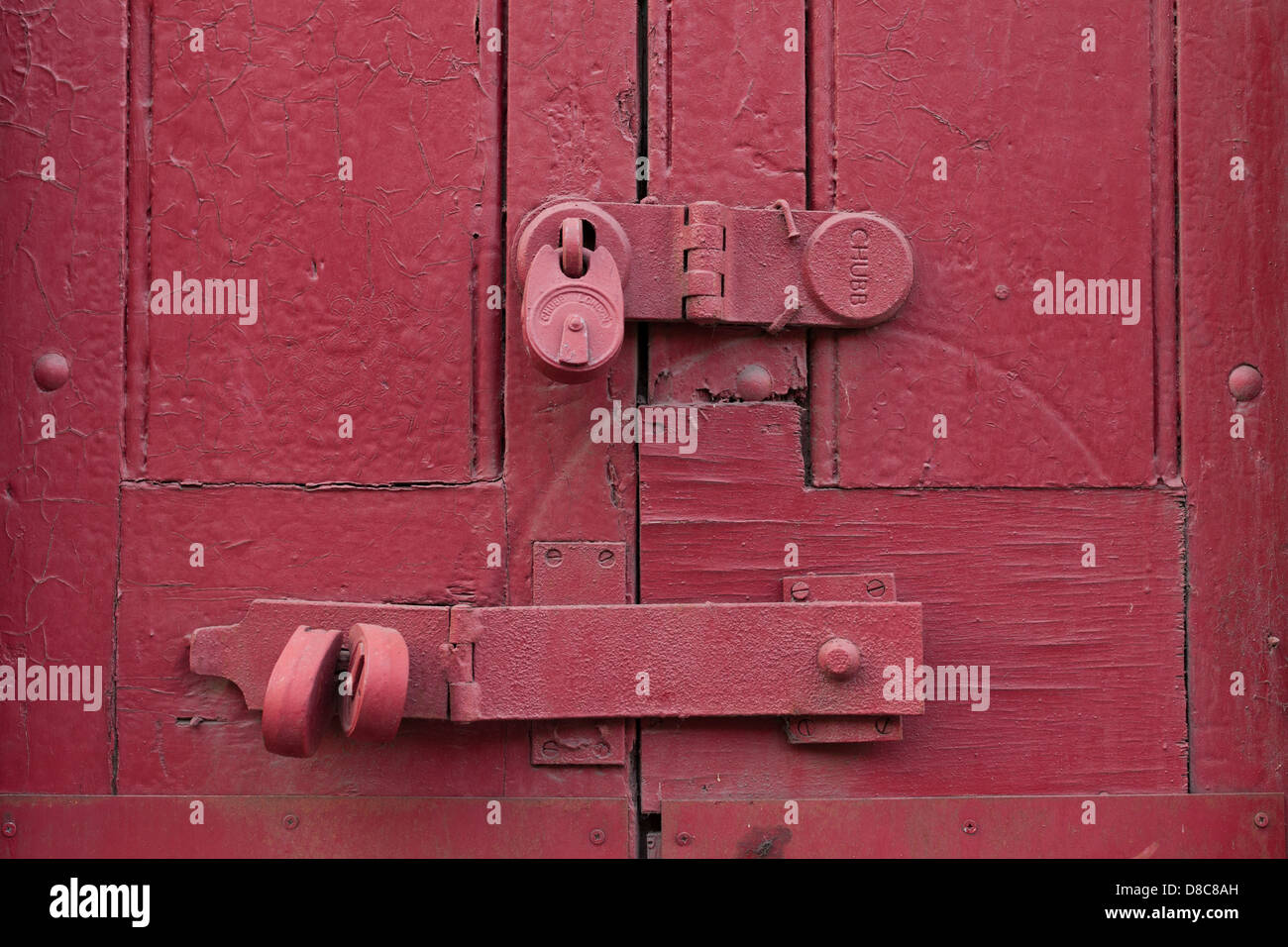 Serrature e cerniere su weathered porta rossa sul molo vecchio edificio, Wapping Foto Stock