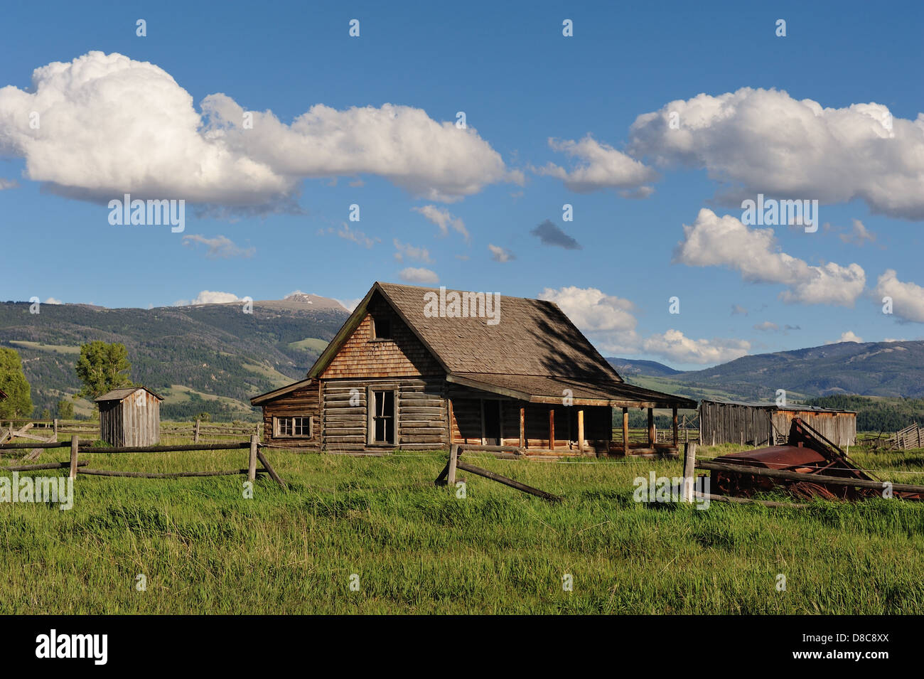 Immagine di un Log Cabin in una prateria, fotografati sotto un cielo blu con pittoresche nuvole bianche. Foto Stock