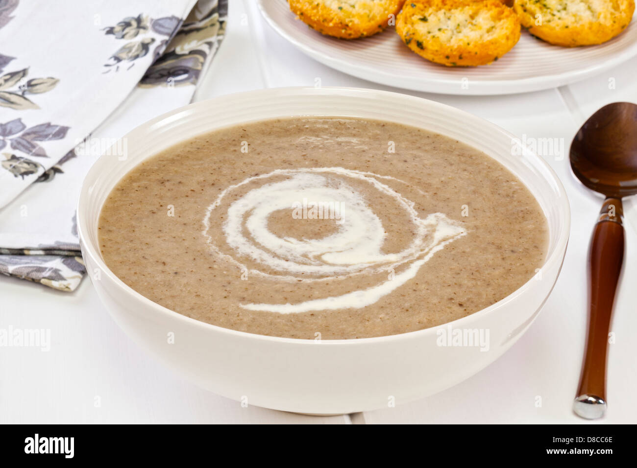 Zuppa di funghi - una ciotola di zuppa di funghi con un turbinio di crème fraiche, servita con pane tostato aglio. Foto Stock