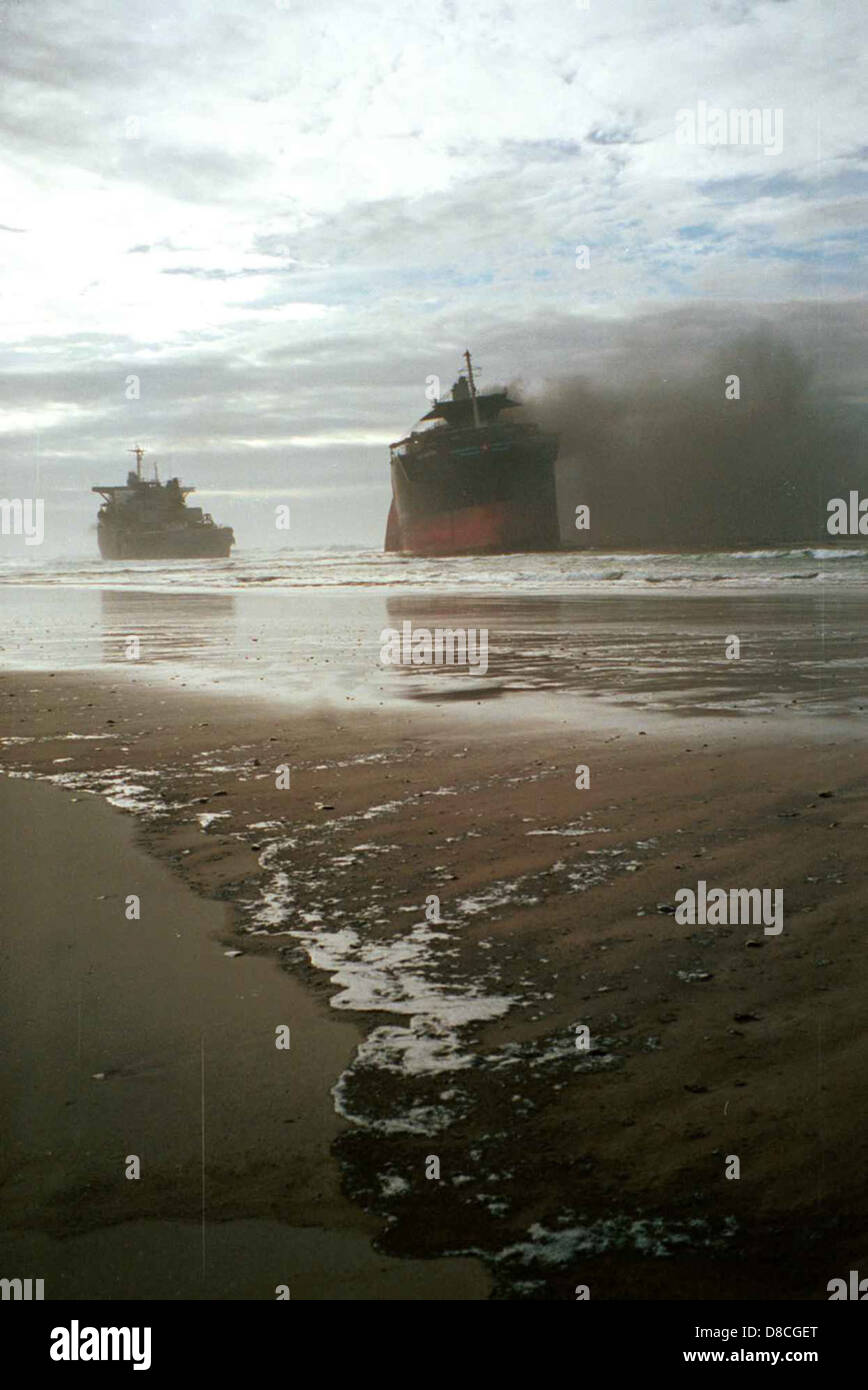 Una scena drammatica che mostra un naufragio in fiamme. La nave in fiamme crea intense fiamme contro l'oceano scuro, segnando la distruzione della nave nell'acqua. Foto Stock