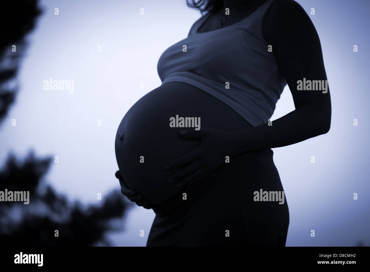 Donna incinta azienda ventre con bracci 9 mese Foto Stock
