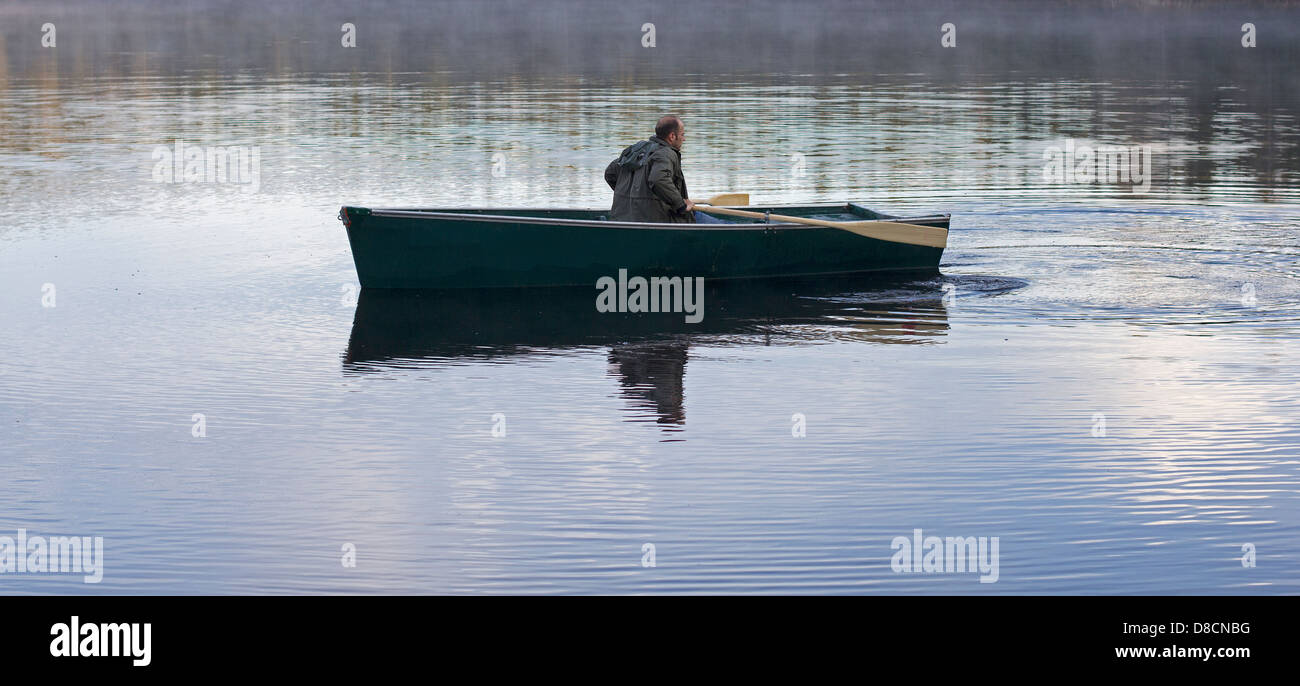 L'uomo canottaggio su un calmo lago selvaggio Foto Stock