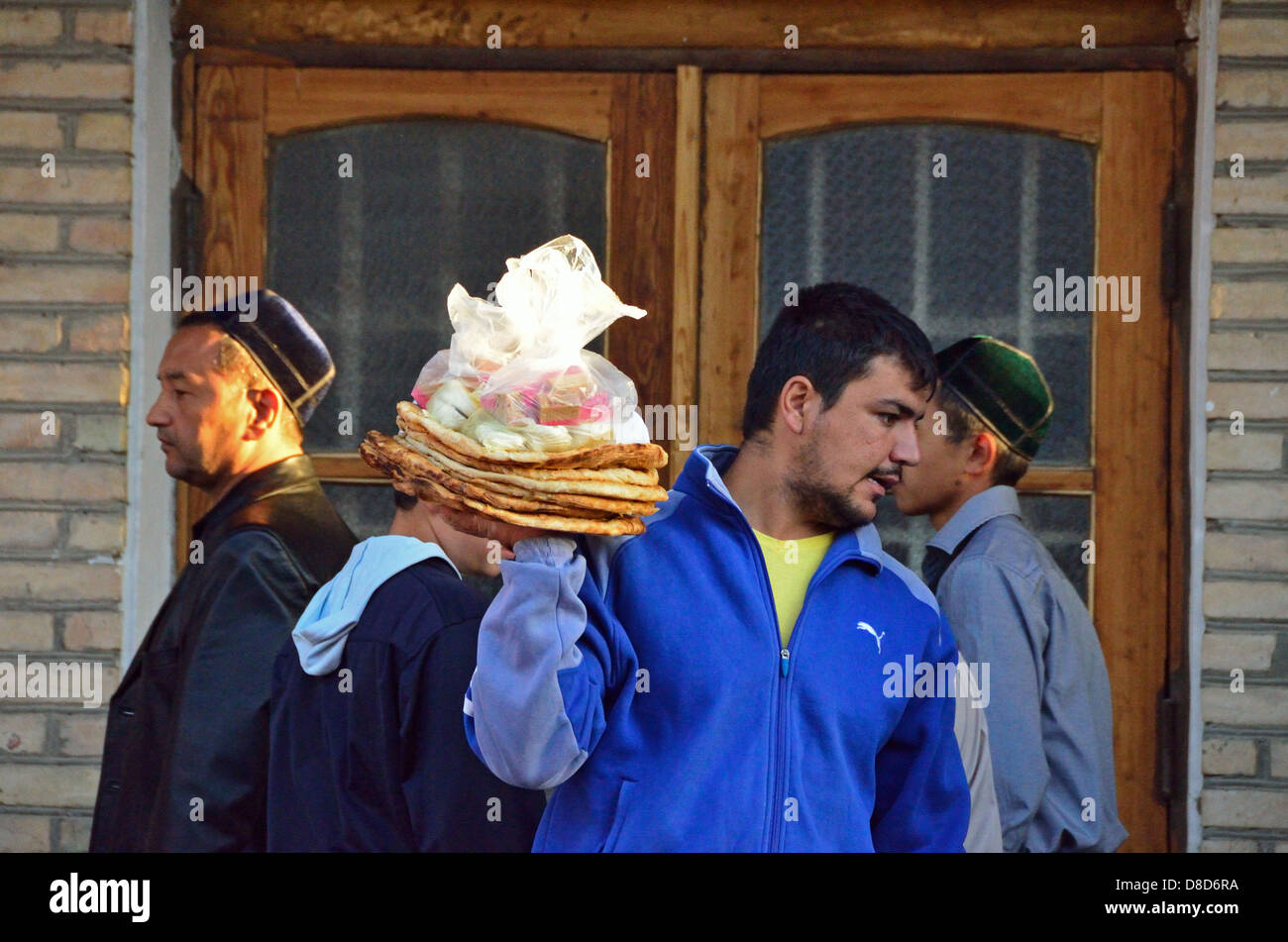 Uzbek uomo vendere allevati (lepyoshka) a Bukhara dopo il ramadan Foto Stock