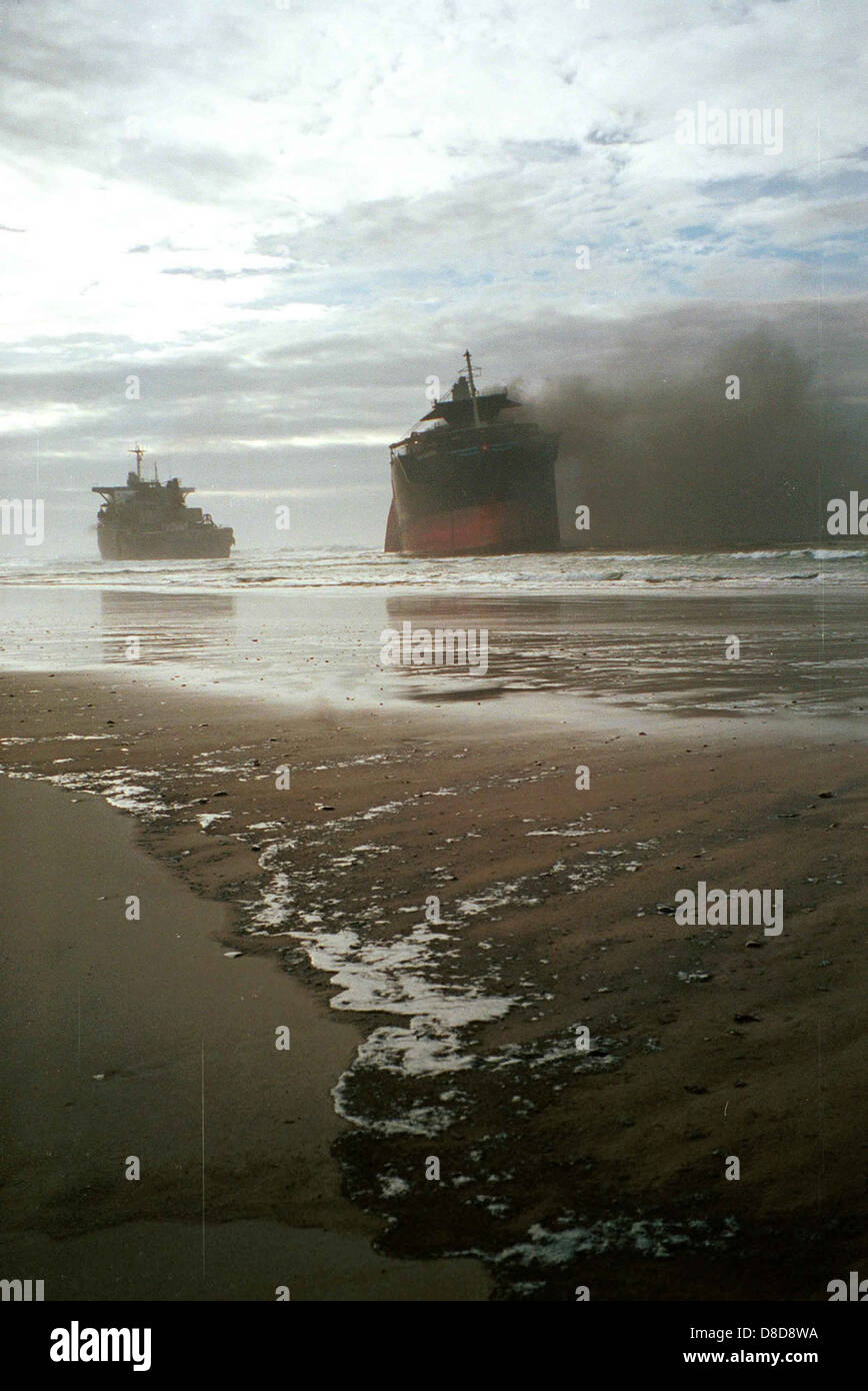 Un naufragio è in fiamme, con fiamme che consumano la struttura. Questa immagine mostra la drammatica scena di una nave in fiamme, probabilmente dopo un disastro marittimo o un incidente. Foto Stock