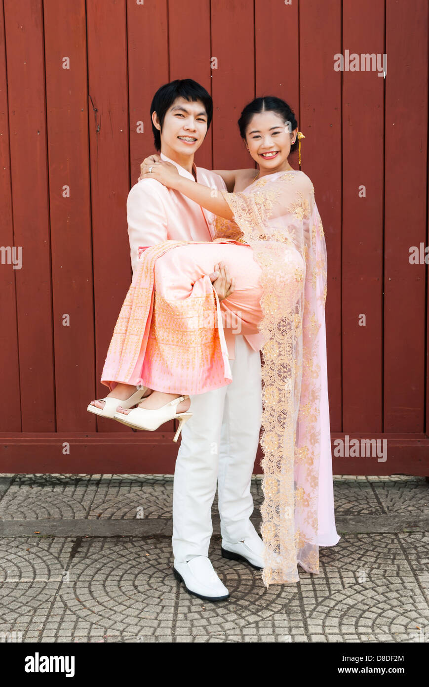 Asian Thai groom sta portando la sua sposa in volto sorridente. Foto Stock