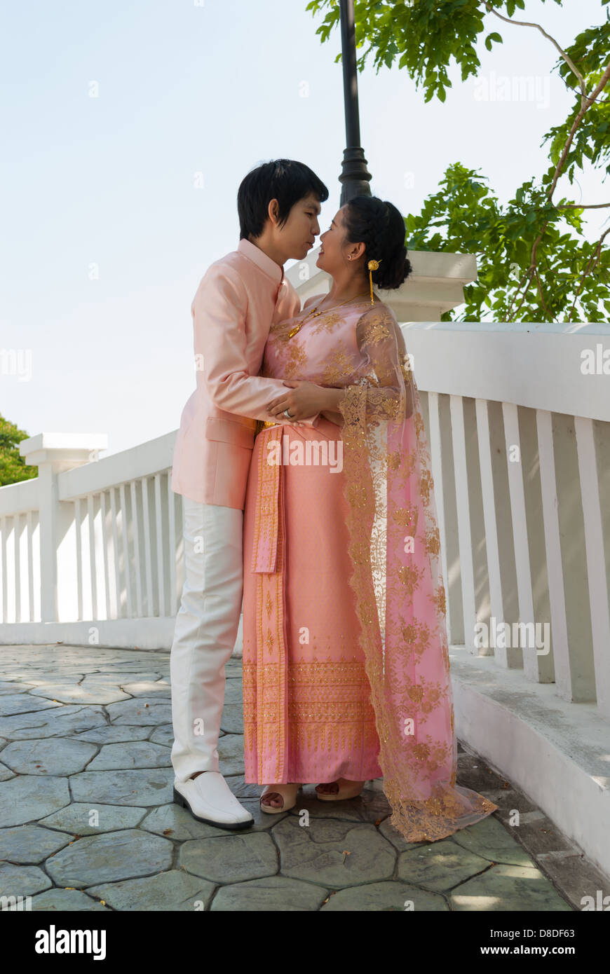 Asian Thai govern è abbracciando la sua sposa accanto a ponte bianco. Foto Stock