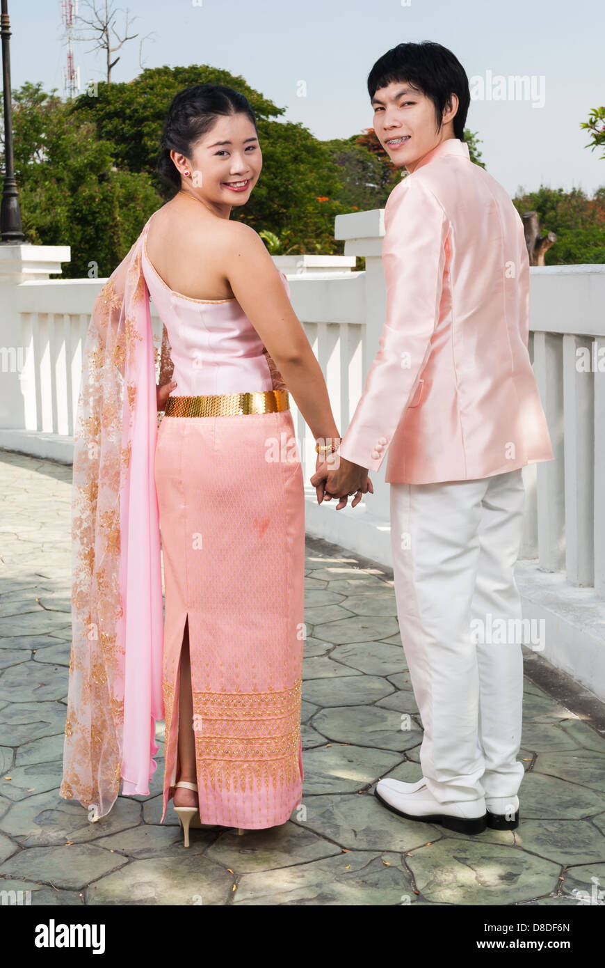 Asian Thai lo sposo è in possesso la sua sposa la mano accanto a ponte bianco. Foto Stock