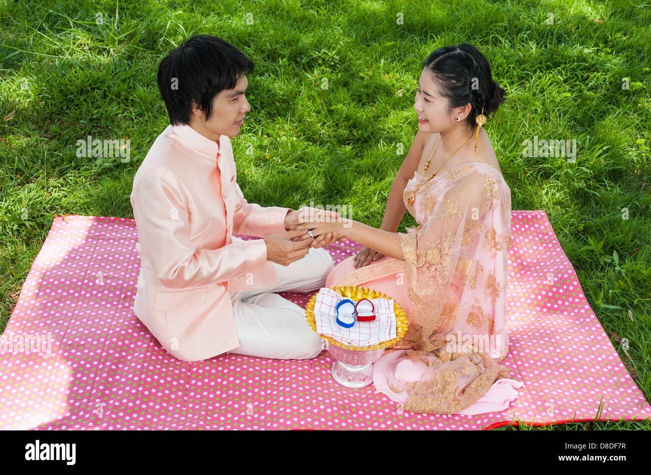 Asian Thai lo sposo indossa anello di nozze alla sua sposa nella cerimonia Thailandese con sensazione di felicità. Foto Stock