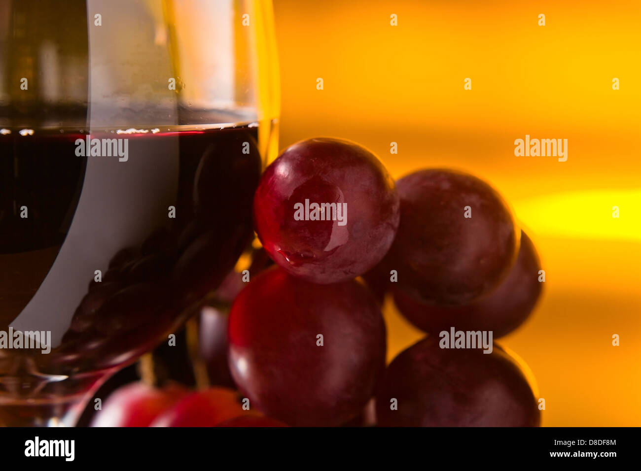 Uva e vetro con vino rosso su sfondo giallo Foto Stock