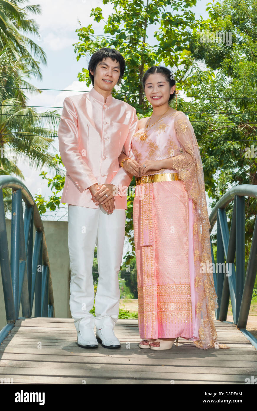 Asian Thai in Nuziale matrimonio Tailandese tuta è in piedi al centro del ponte blu. Foto Stock