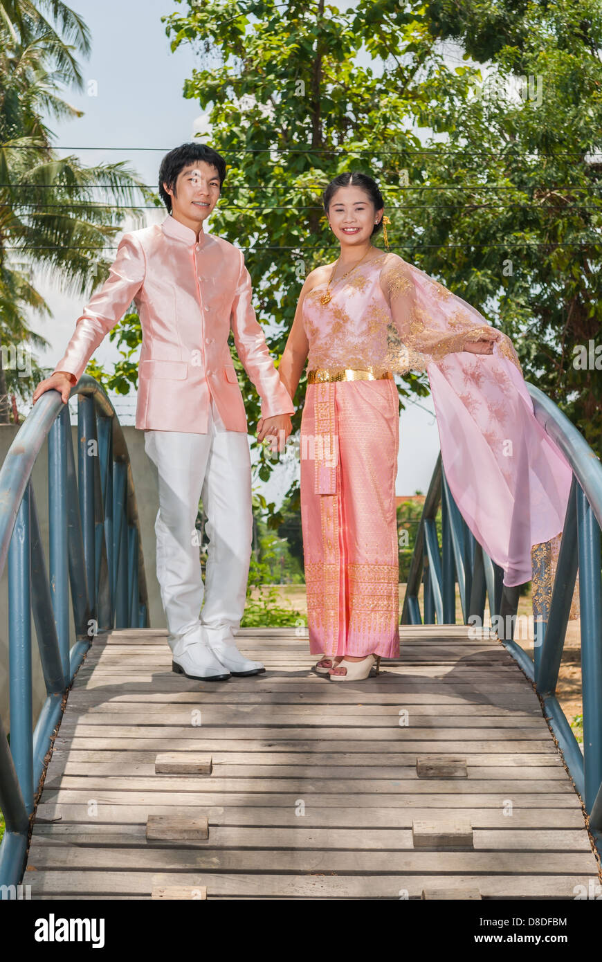 Asian Thai in Nuziale matrimonio Tailandese tuta sta tenendo in mano la metà del ponte blu. Foto Stock
