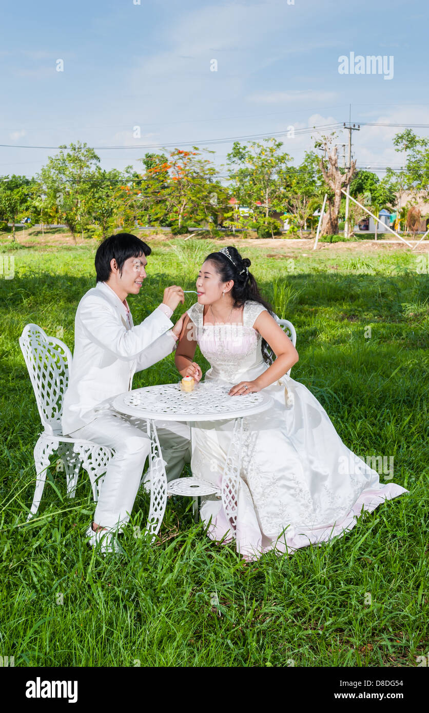 Asian Thai lo sposo è la alimentazione del pezzo di torta di nozze alla sua sposa nel momento in cui il principe e la principessa. Foto Stock