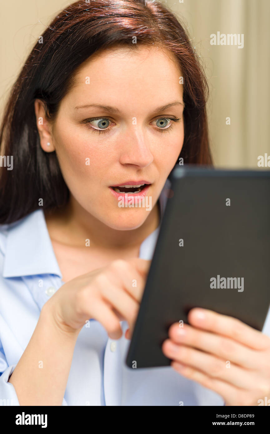 Faccia stupita espressione della donna lettura sulla tavoletta digitale Foto Stock