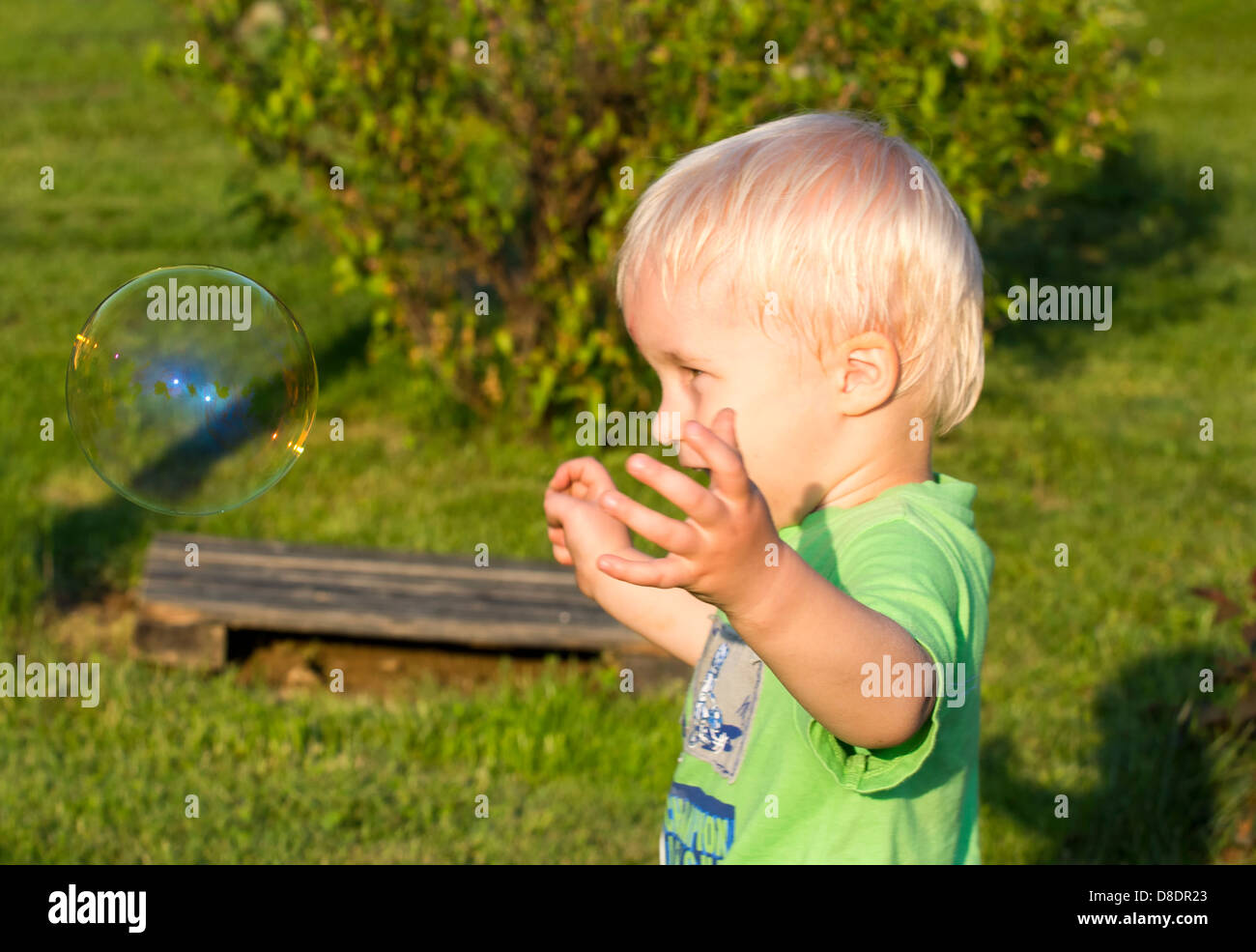 Il Toddler boy divertendosi con bolle di sapone. Foto Stock