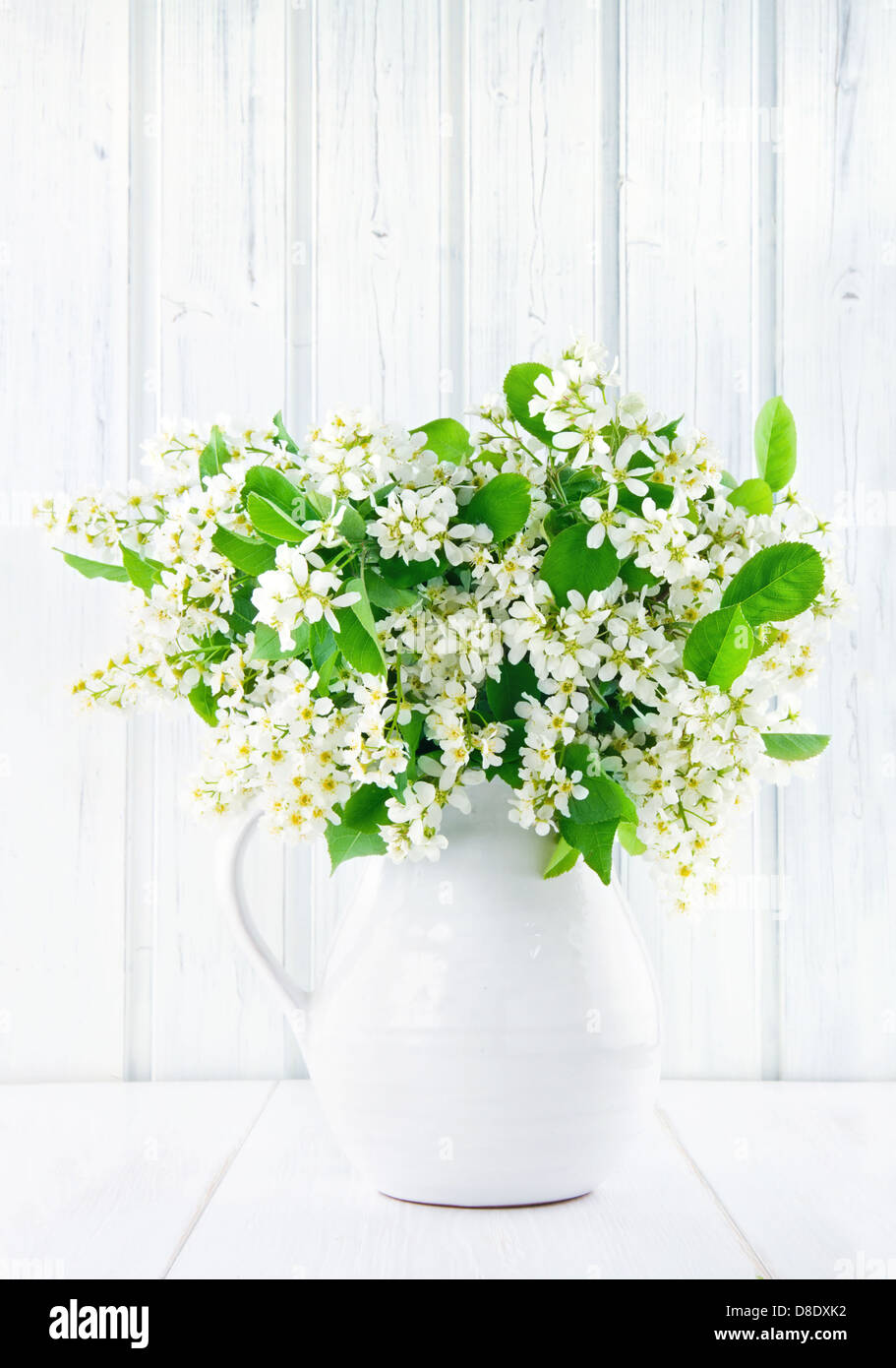 Bouquet di White Bird Rami di Ciliegio in una caraffa in ceramica su vintage tavolo in legno Foto Stock