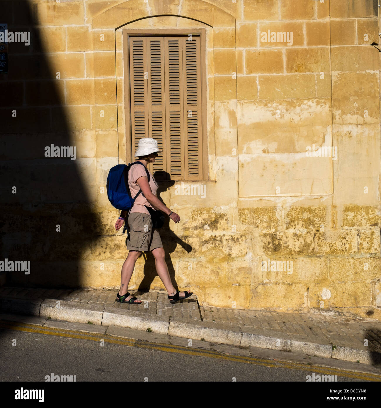 La donna che porta un piccolo back pack passeggiate in discesa indossando un cappello Foto Stock