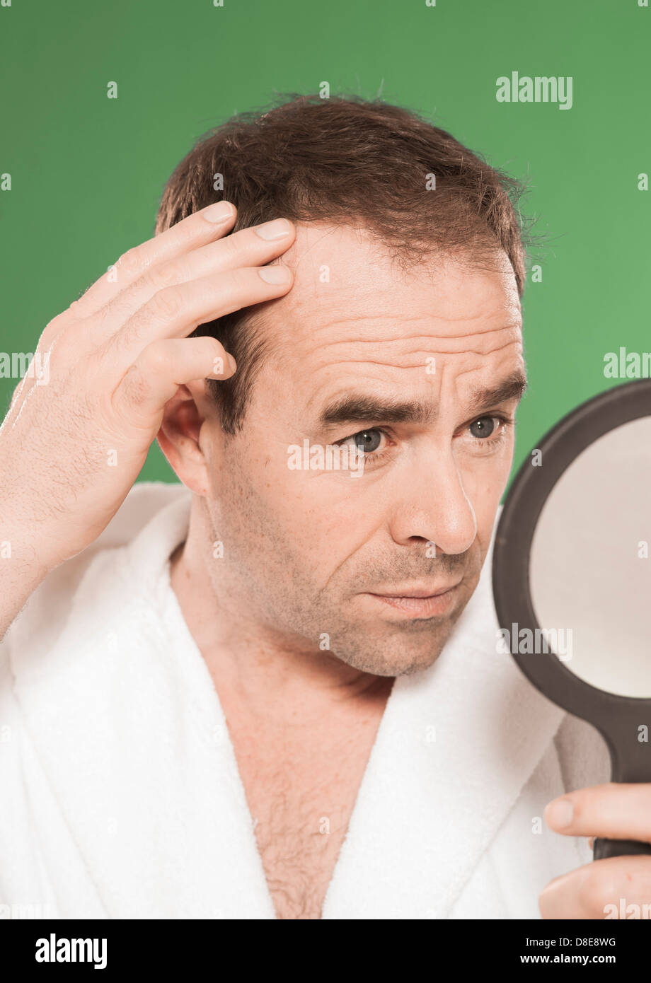 Uomo in accappatoio cercando in specchio per il make-up Foto Stock