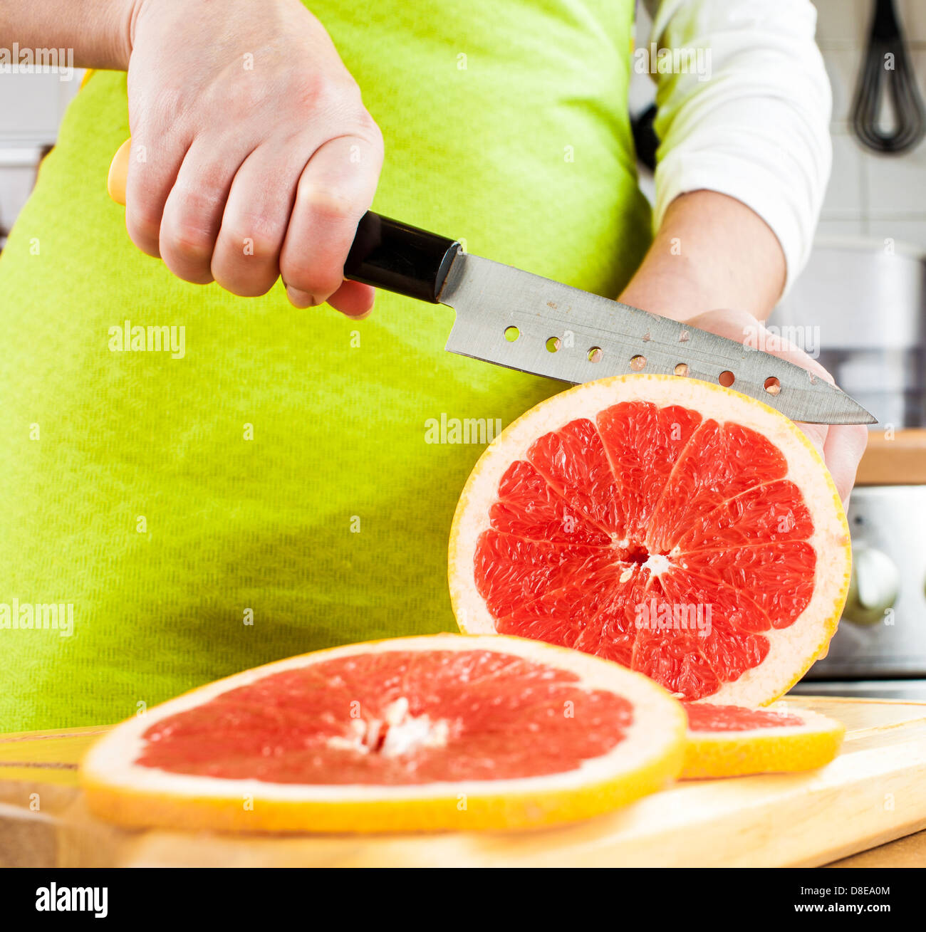 Donna con le mani in mano il taglio di succo di pompelmo fresco su cucina Foto Stock