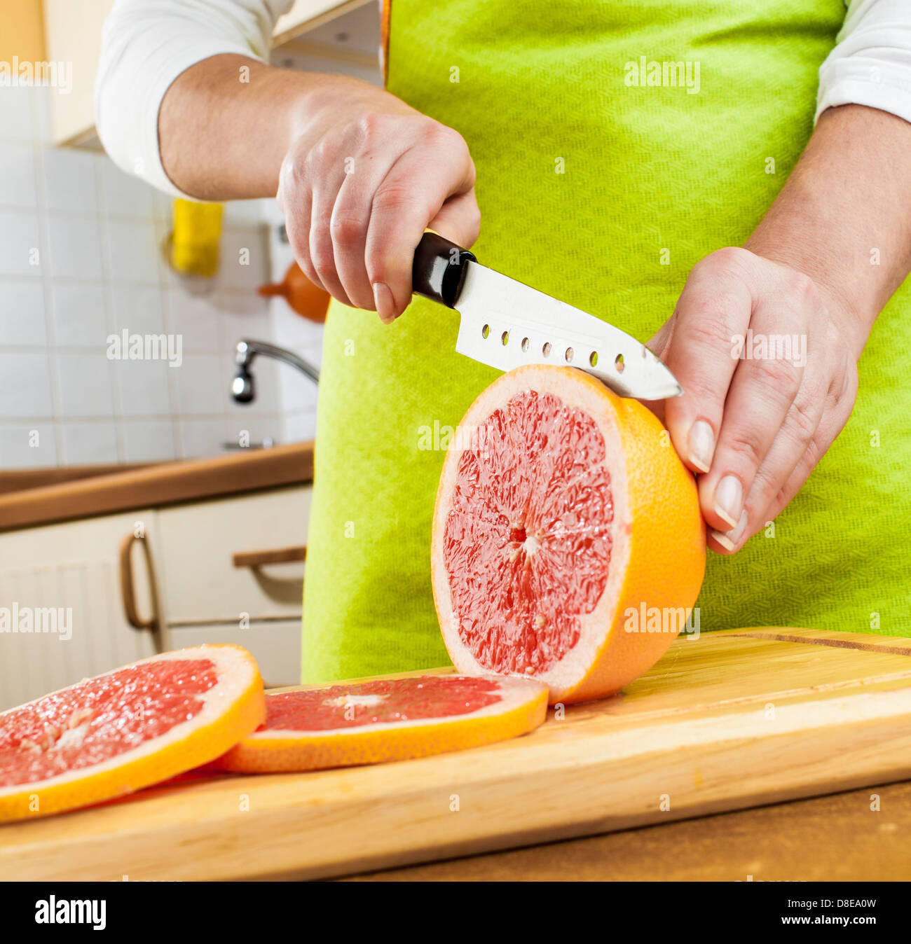 Donna con le mani in mano il taglio di succo di pompelmo fresco su cucina Foto Stock