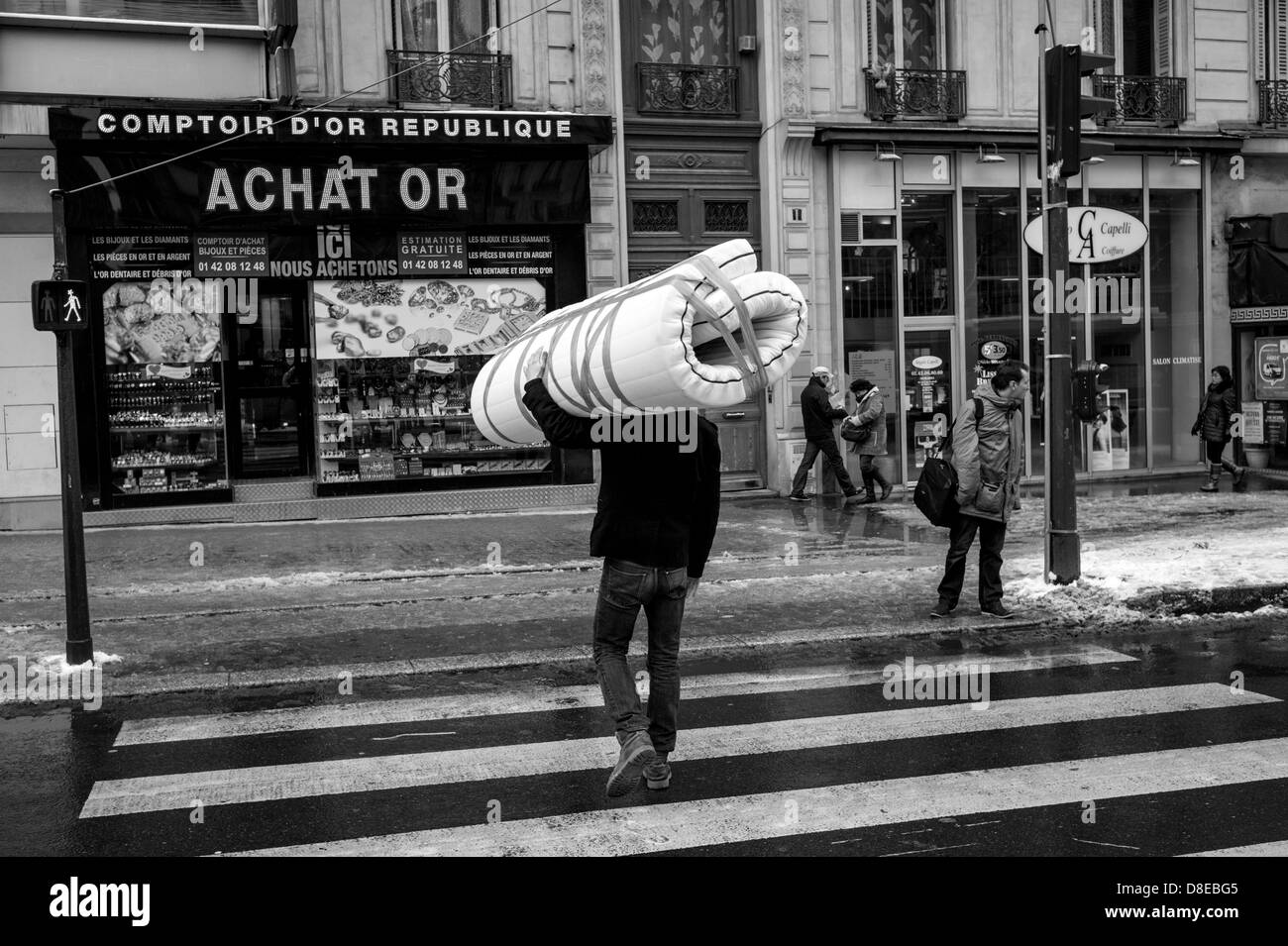 Uomo che porta un materasso attraverso una strada di Parigi. Foto Stock