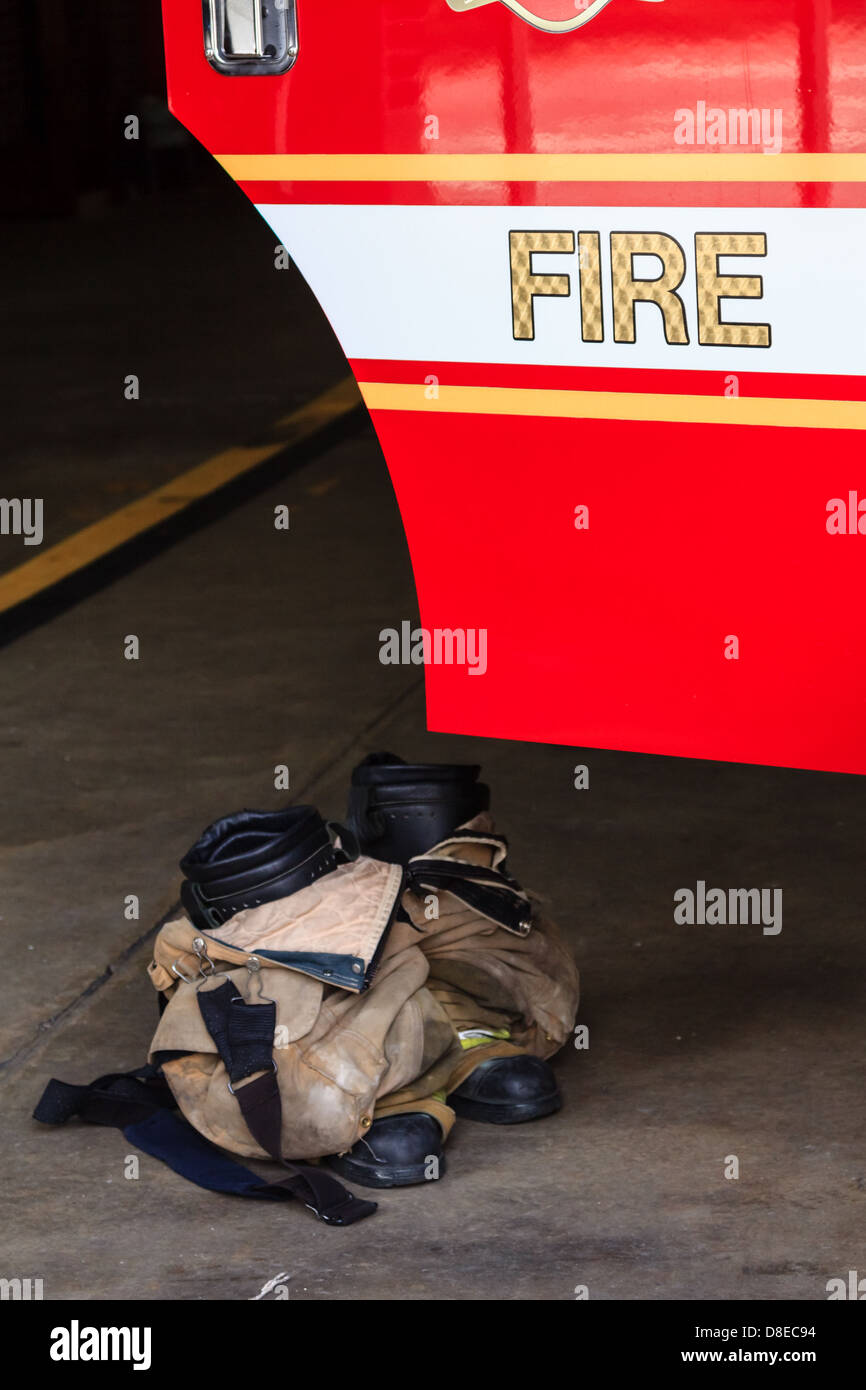 Stivali di vuoto e i vestiti di un vigile del fuoco nella parte anteriore della portiera di una macchina Foto Stock