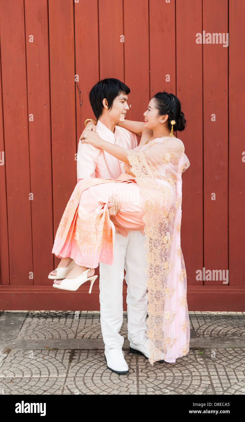 Asian Thai groom sta portando la sua sposa in volto sorridente. Foto Stock