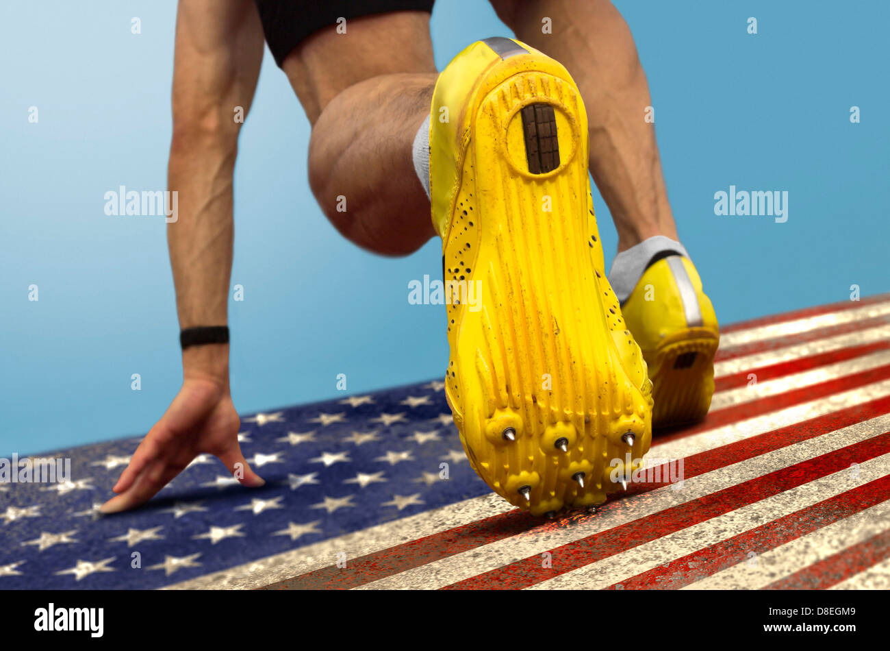 Sprinter con picchi è in posizione di avviamento su grungy noi bandiera Foto Stock