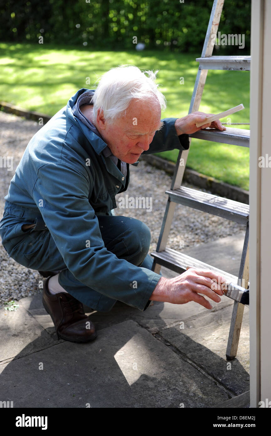 75 anni di pittura pensionato il portico di casa sua nel North Yorkshire, Inghilterra, Regno Unito Foto Stock