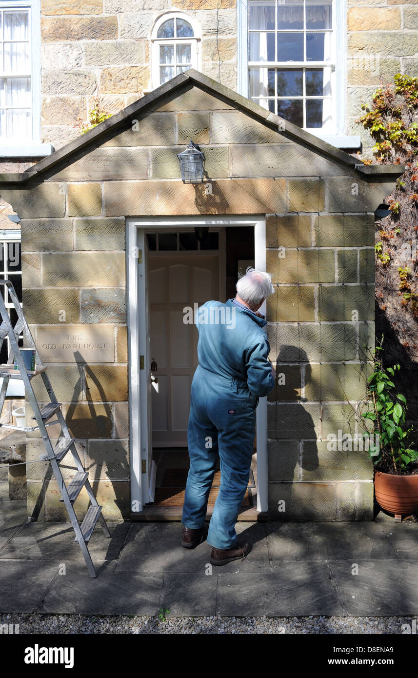 75 anni di pittura pensionato il portico di casa sua nel North Yorkshire, Inghilterra, Regno Unito Foto Stock
