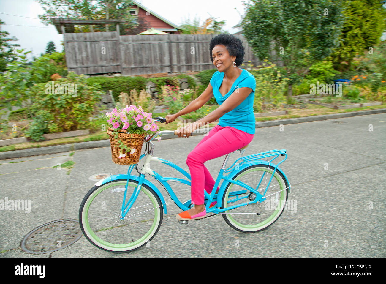 Donna di equitazione Bicicletta retrò con cesto fiorito Foto Stock