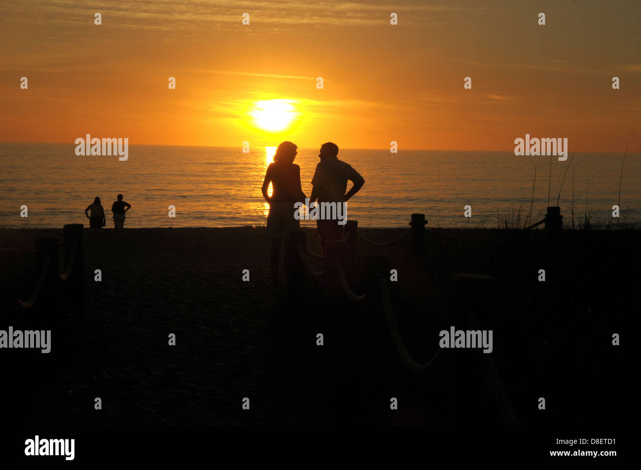 Un giovane tenere mani come i tramonti in Englewood, Florida sulla spiaggia. Foto Stock