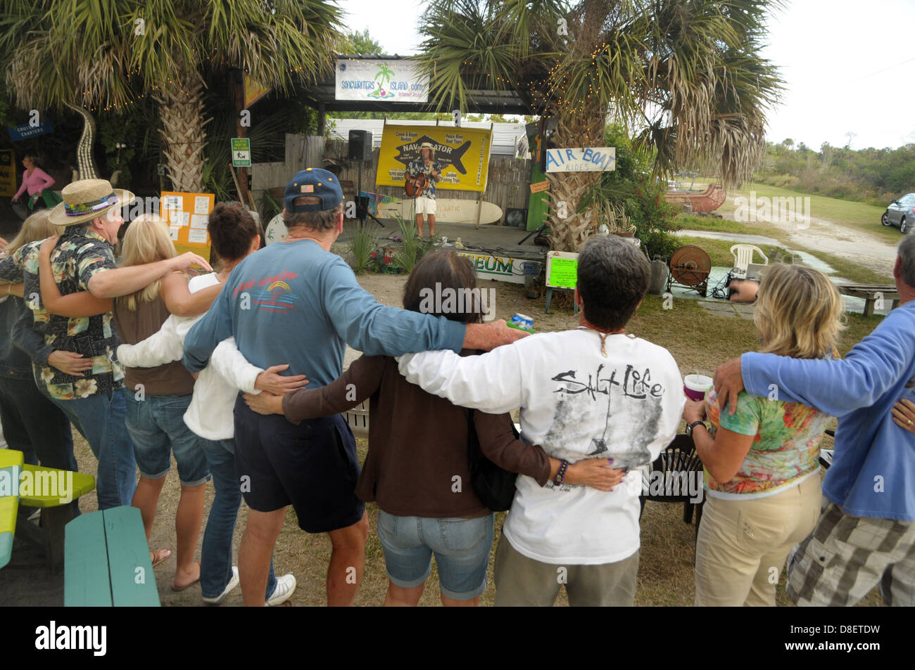 Un gruppo di frequentatori del bar bloccare i bracci che ascoltano un intrattenitore al Lago di Suzy, Florida. Foto Stock