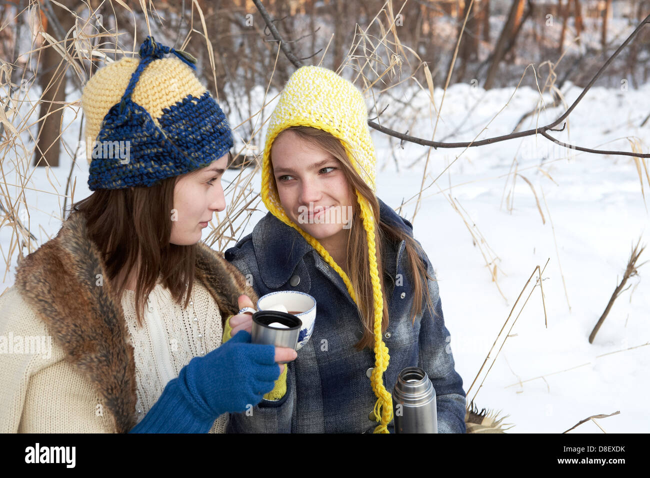 Teen sorelle che condividono una cioccolata calda in inverno wonderland Foto Stock