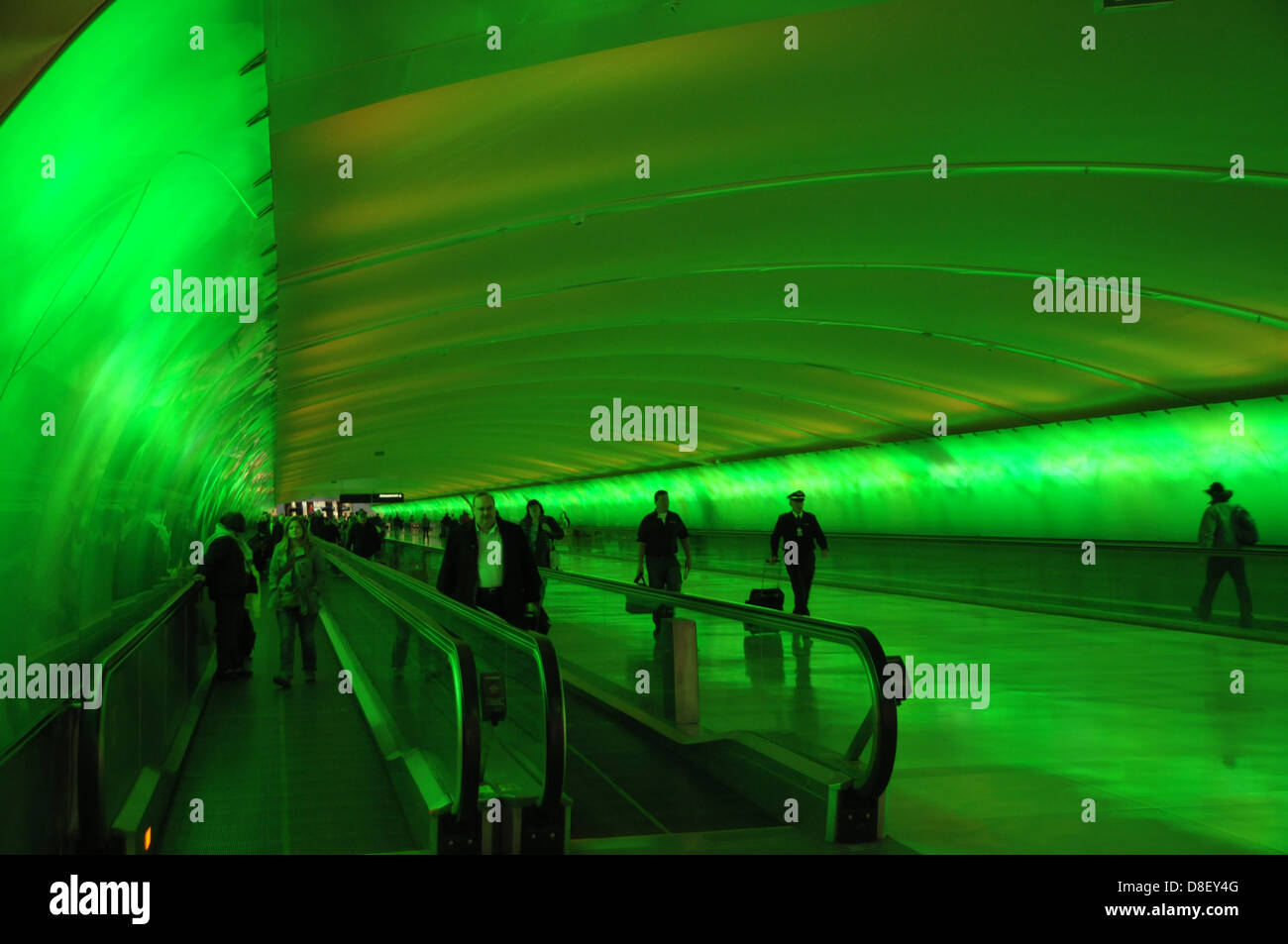 Un tappeto mobile porta i viaggiatori verso la loro destinazione a Detroit Aeroporto Internazionale come luci colorate illuminano la via. Foto Stock