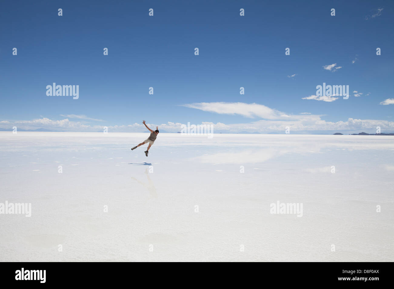 L'uomo danze in un tetro bianco paesaggio delle Saline di Uyuni in Bolivia Foto Stock